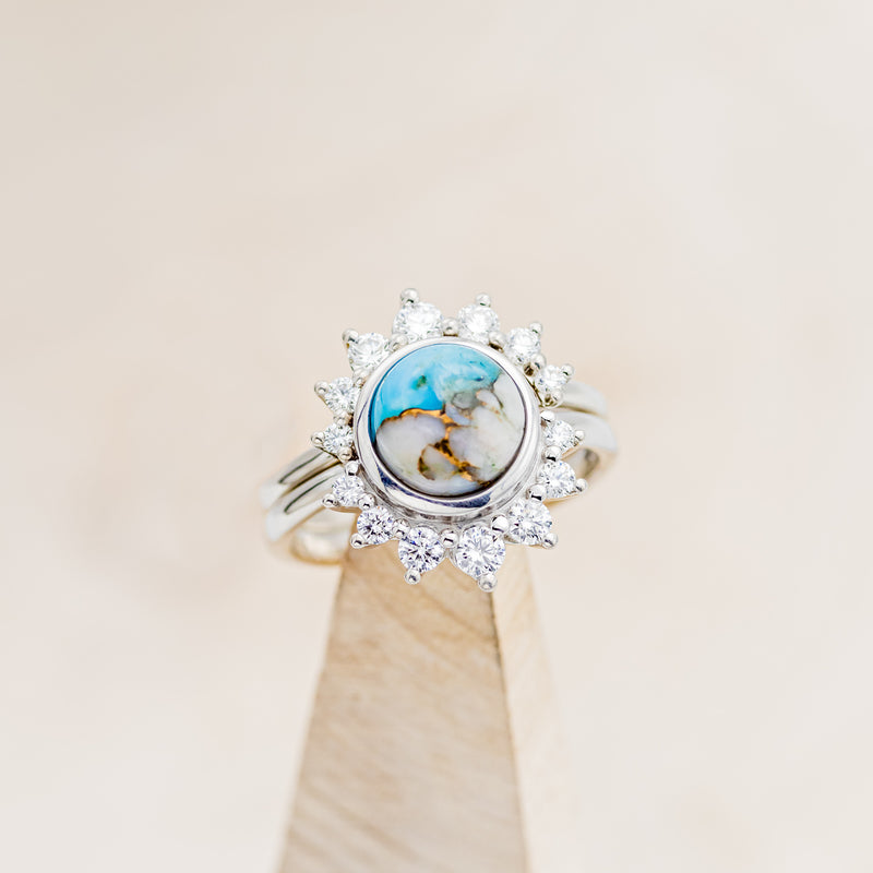 Shown here is "Esmeralda", a round cut spiny oyster turquoise women's engagement ring with diamond accents and a diamond tracer, on stand front facing. Many other center stone options are available upon request.