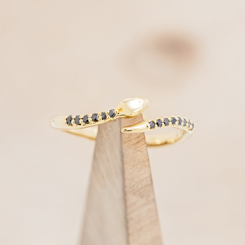 Shown here is "Serpent", a snake-style wedding band featuring black diamond accents, on stand front facing.