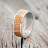 Shown here is "Rainier", a handcrafted men's wedding ring featuring a whiskey barrel oak inlay, upright facing left. 
