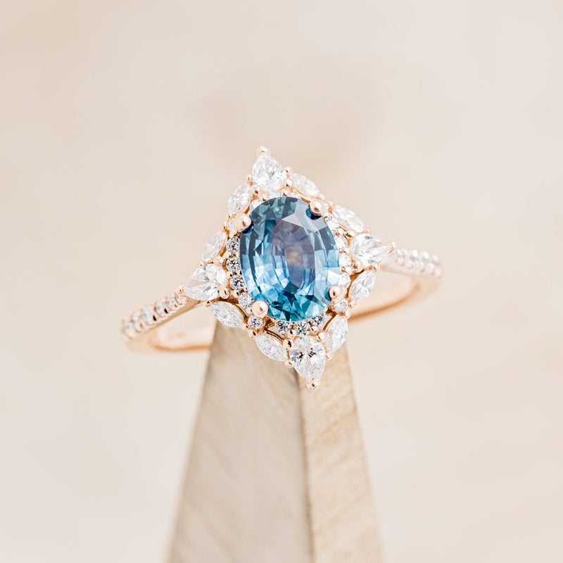 Shown here is The "North Star", a halo-style oval Montana sapphire women's engagement ring, on stand front facing, with delicate and ornate details and is available with many center stone options-Custom Engagement Ring - Vintage Style Engagement Ring - Staghead Designs