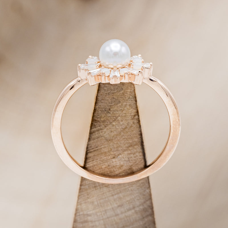 Shown here is "Dorothea", a white Akoya pearl women's engagement ring with opal and diamond accents, side view on stand. Many other center stone options are available upon request.