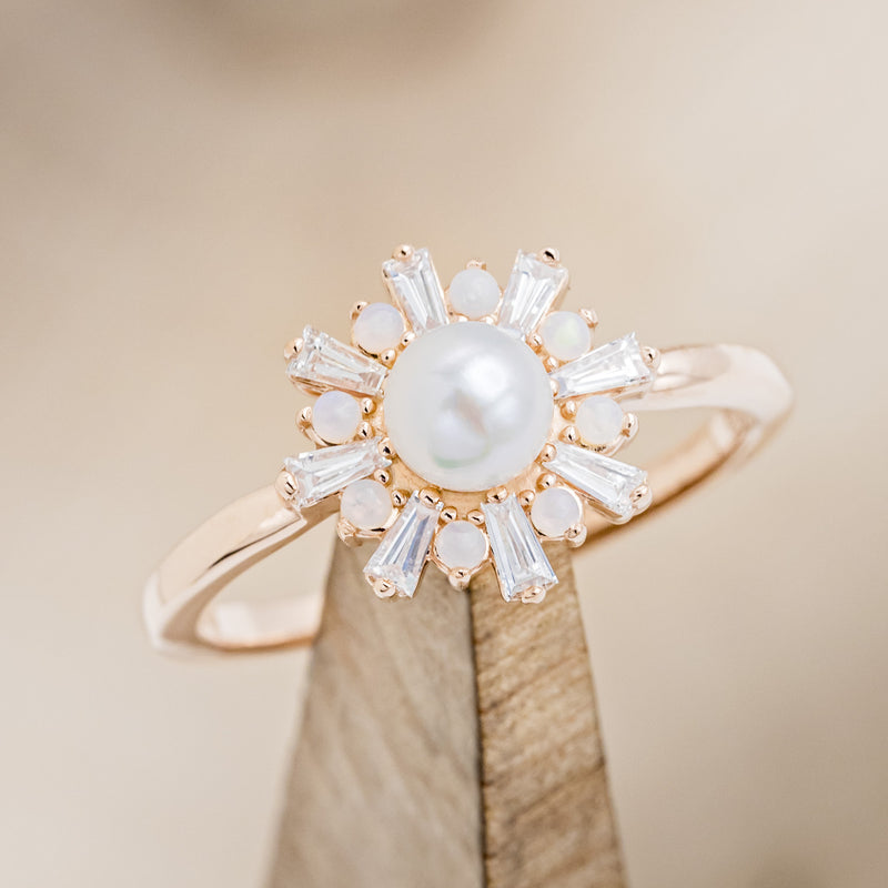 Shown here is "Dorothea", a white Akoya pearl women's engagement ring with opal and diamond accents, on stand tilted right. Many other center stone options are available upon request.