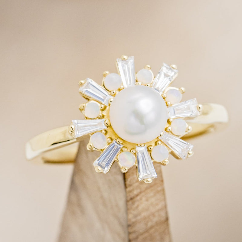 Shown here is "Dorothea", a white Akoya pearl women's engagement ring with opal and diamond accents, on stand facing slightly right. Many other center stone options are available upon request. 