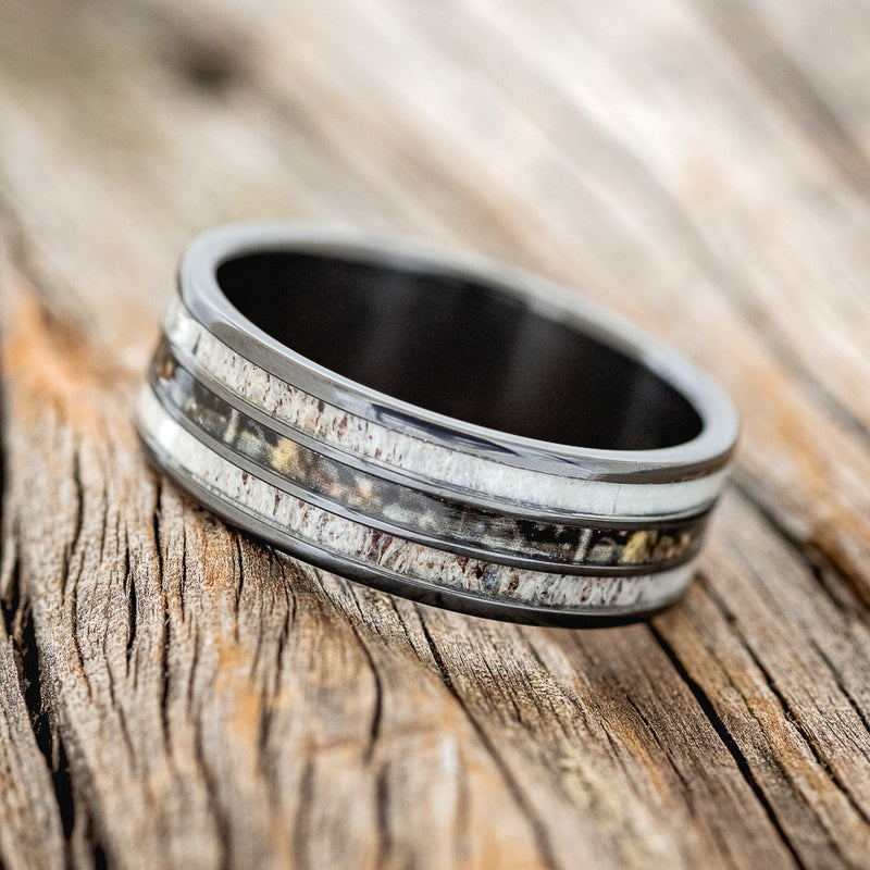 Shown here is "Rio", a custom, handcrafted men's wedding ring featuring 3 channels with antler and camo inlays, tilted left. Additional inlay options are available upon request.