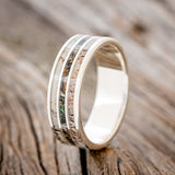 Shown here is "Rio", a custom, handcrafted men's wedding ring featuring 3 channels with antler and camo inlays, upright facing left. Additional inlay options are available upon request.
