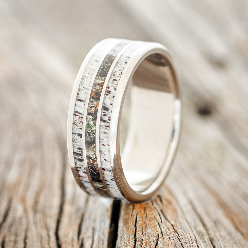 Shown here is "Rio", a custom, handcrafted men's wedding ring featuring 3 channels with antler and camo inlays, upright facing left.