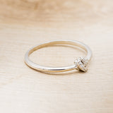 Shown here is a dainty-style knot women's stacking band with diamond accents, facing right.
