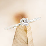 Shown here is a dainty-style knot women's stacking band with diamond accents, on stand front facing. 