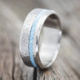 Shown here is "Vertigo", a custom, handcrafted men's wedding ring featuring a turquoise inlay with a hammered finish, upright facing left. Additional inlay options are available upon request.