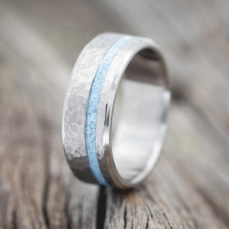 Shown here is "Vertigo", a handcrafted men's wedding ring featuring a turquoise inlay with a hammered finish, upright facing left.