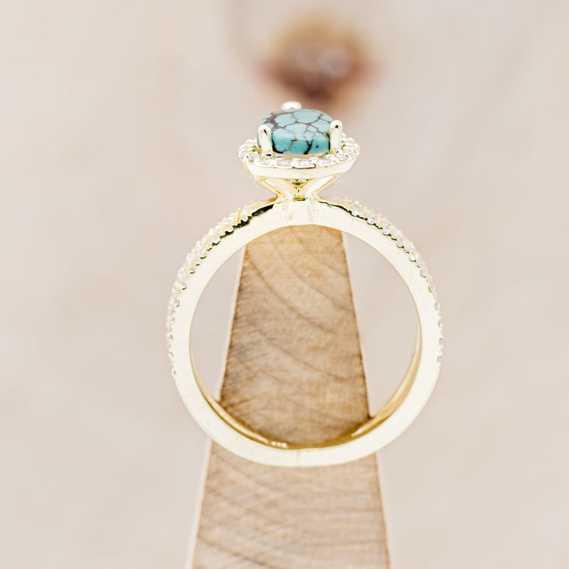 Shown here is "Nala", a split shank-style turquoise women's engagement ring with a diamond halo and diamond accents, side view on stand. Many other center stone options are available upon request.