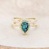 Shown here is "Nala", a split shank-style turquoise women's engagement ring with a diamond halo and diamond accents, front facing. Many other center stone options are available upon request.