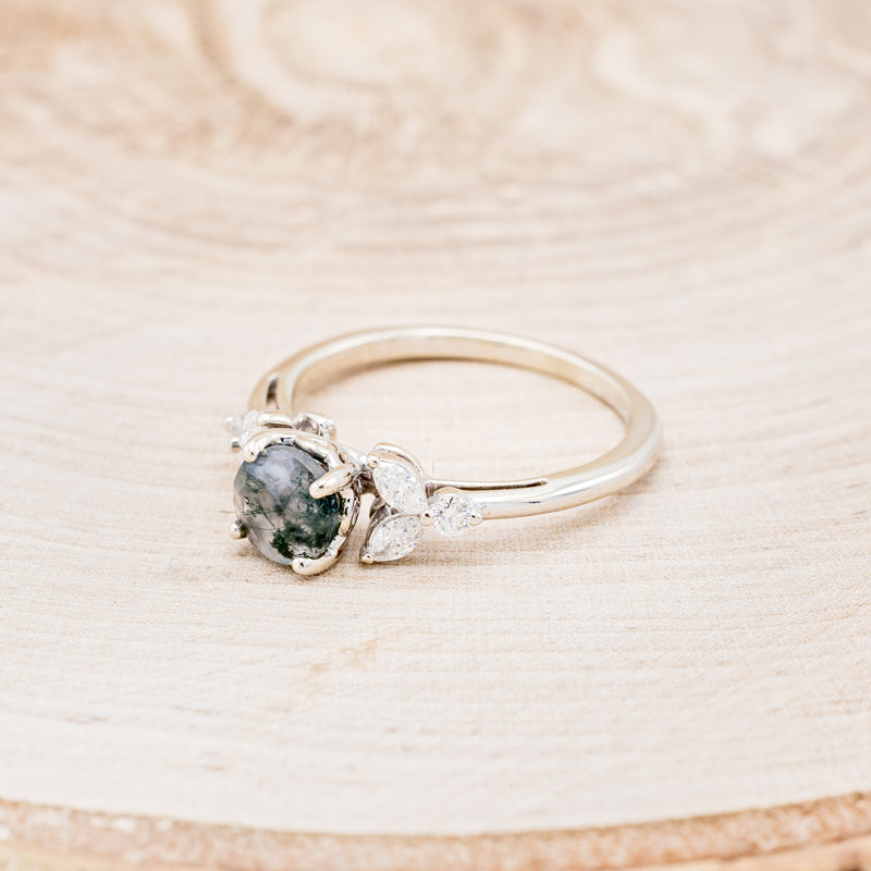 Shown here is "Blossom", a moss agate women's engagement ring with leaf-shaped diamond accents, facing left. Many other center stone options are available upon request.