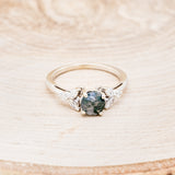 Shown here is "Blossom", a moss agate women's engagement ring with leaf-shaped diamond accents, front facing. Many other center stone options are available upon request.