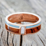 Shown here is "Bower", a custom, handcrafted men's wedding ring featuring a vertical channel with mother of pearl and 2 horizontal channels with turquoise and ironwood inlays, laying flat. Additional inlay options are available upon request.