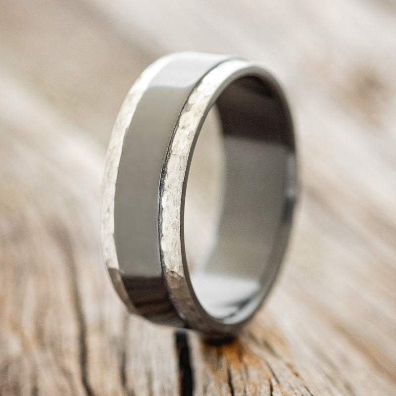 Shown here is "Sedona", a handcrafted men's wedding ring featuring fire-treated black zirconium with hand-hammered edges, upright facing left. The edges are hammered after the heat treatment, which means they are a silver/gray color rather than black