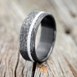 Shown here is "Vertigo", a custom, handcrafted hammered men's wedding ring featuring an antler inlay on a fire-treated black zirconium band, upright facing left. Additional inlay options are available upon request.