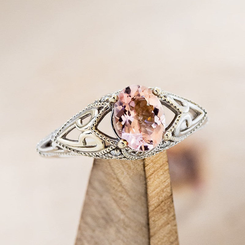 Shown here is "Relica", a vintage-style morganite women's engagement ring with diamond accents, on stand facing slightly right. Many other center stone options are available upon request.