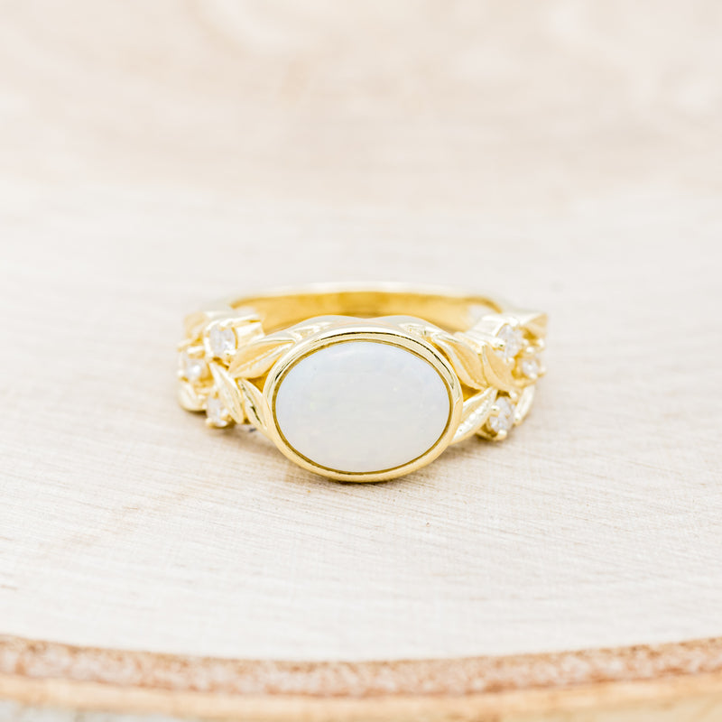 Shown here is "Elora", a vintage-style opal engagement ring with a delicate floral pattern and diamond accents, front facing. Many other center stone options are available upon request.