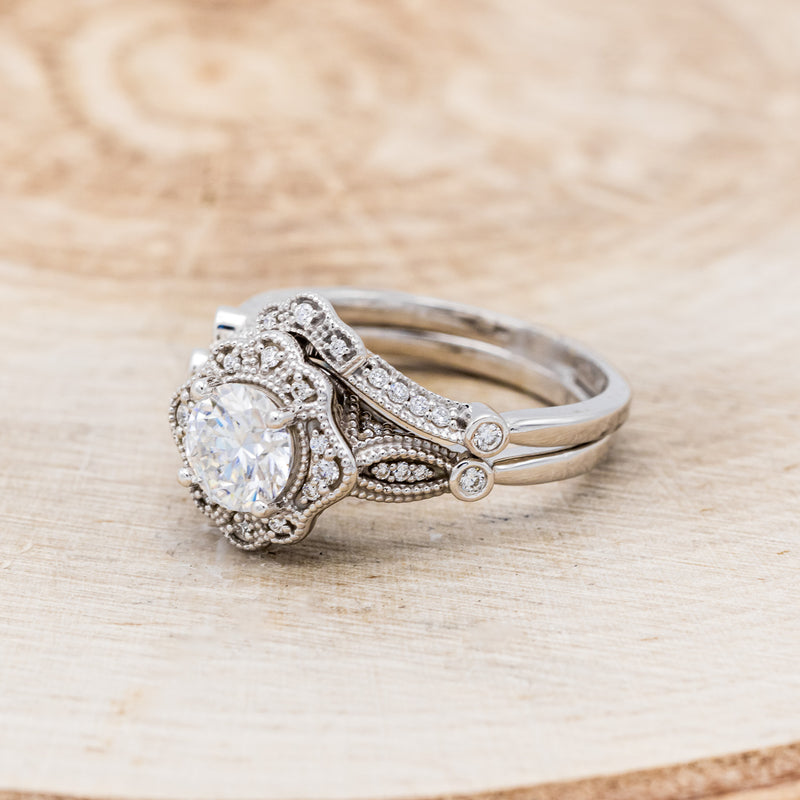 Shown here is "Eileen", a vintage-style moissanite women's engagement ring with a diamond halo, accents, and tracer, facing left. Many other center stone options are available upon request.