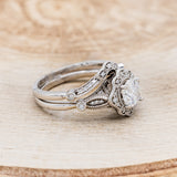 Shown here is "Eileen", a vintage-style moissanite women's engagement ring with a diamond halo, accents, and tracer, facing right. Many other center stone options are available upon request.