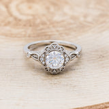 Shown here is "Eileen", a vintage-style moissanite women's engagement ring with a diamond halo, accents, front facing. Many other center stone options are available upon request.