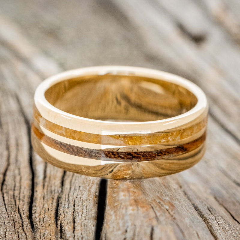 Shown here is "Cosmo", a custom, handcrafted men's wedding ring featuring two offset inlays with amber and ironwood inlays, laying flat. Additional inlay options are available upon request.