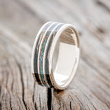 Shown here is "Rio", a custom, handcrafted men's wedding featuring 3 channels with patina copper and duck feather inlays on a titanium band, upright facing left. Additional inlay options are available upon request.