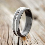 Shown here is "Nirvana", a handcrafted men's wedding ring featuring an antler inlay on a fire-treated black zirconium band, upright facing left.