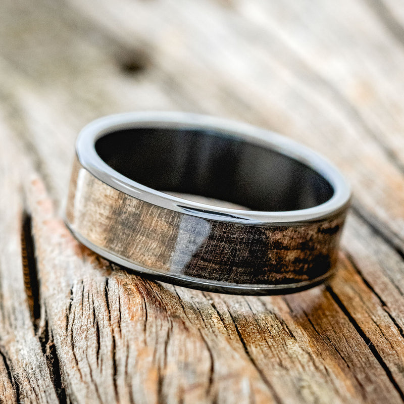 Shown here is "Rainier", a custom, handcrafted men's wedding ring featuring dark maple wood inlay, shown here on a fire-treated black zirconium band, tilted left. Additional inlay options are available upon request.