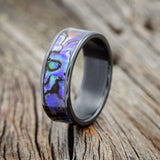Shown here is "Rainier", a handcrafted men's wedding ring featuring a paua shell inlay, upright facing left. 
