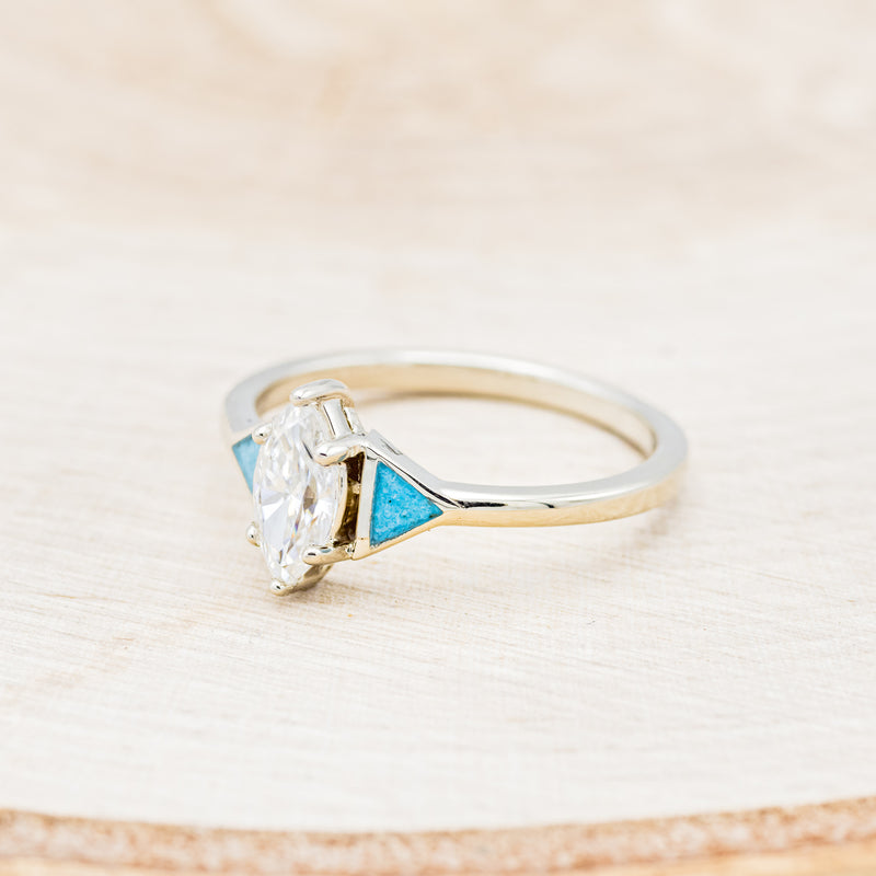 Shown here is "Nile", an art deco-style moissanite women's engagement ring with turquoise inlays and tracer, facing left. Many other center stone options are available upon request.