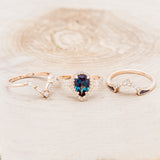 Shown here is "KB", a bridal suite-style lab-created alexandrite women's engagement ring with diamond accents, "Melody" tracer, and "Sama" tracer, laying together. Many other center stone options are available upon request.