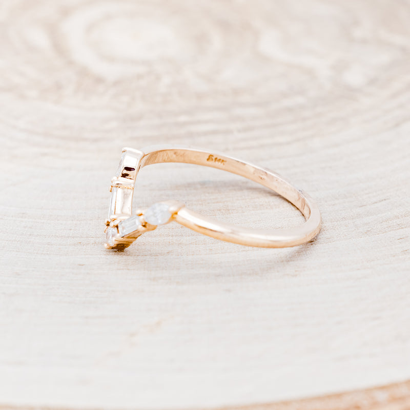 Shown here is "Melody", a 14K gold v-shaped band with diamond accents, facing left.
