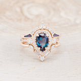 Shown here is "KB", a bridal suite-style lab-created alexandrite women's engagement ring with diamond accents, "Melody" tracer, and "Sama" tracer, front facing. Many other center stone options are available upon request.