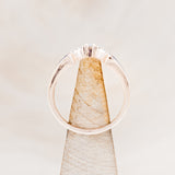 Shown here is "Sama", a 14K gold band with acrylic inlays and diamond accents, side view on stand.