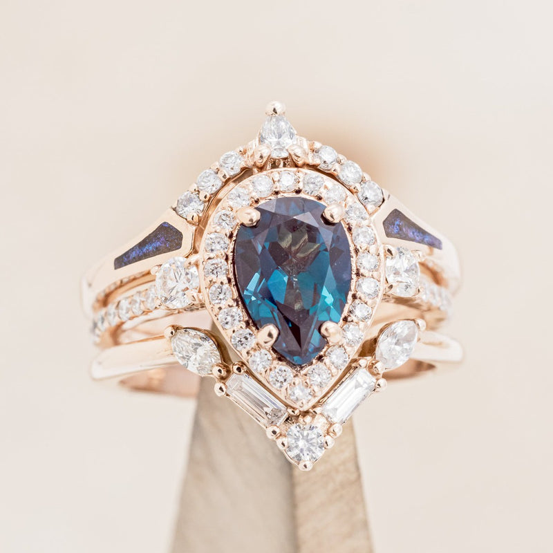 Shown here is "KB", a bridal suite-style lab-created alexandrite women's engagement ring with diamond accents, "Melody" tracer, and "Sama" tracer, on stand front facing. Many other center stone options are available upon request. 
