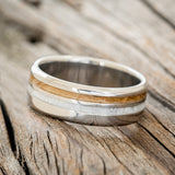 Shown here is "Cosmo", a custom, handcrafted men's wedding ring featuring whiskey barrel oak and antler inlays, tilted left. Additional inlay options are available upon request.