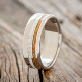 Shown here is "Cosmo", a custom, handcrafted men's wedding ring featuring whiskey barrel oak and antler inlays, upright facing left. Additional inlay options are available upon request.