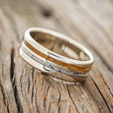 Shown here is "Cosmo", a custom, handcrafted men's wedding ring featuring whiskey barrel oak and antler inlays, tilted left. Additional inlay options are available upon request.