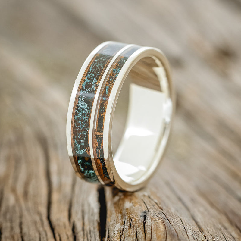 Shown here is "Raptor", a custom, handcrafted men's wedding ring featuring patina copper inlays, upright facing left. Additional inlay options are available upon request.