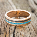 Shown here is "Cosmo", a custom, handcrafted men's wedding ring featuring 2 channels with a turquoise and a patina copper inlay, laying flat. Additional inlay options are available upon request.