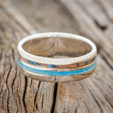 Shown here is "Cosmo", a custom, handcrafted men's wedding ring featuring 2 channels with a turquoise and a patina copper inlay, laying flat. Additional inlay options are available upon request.