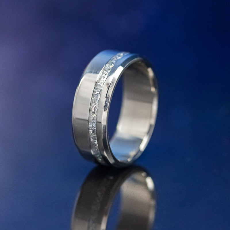 Shown here is "Vertigo", a custom, handcrafted men's wedding ring featuring a diamond dust inlay, shown here set in a titanium band, upright facing left. the inlay is called Diamond dust, which is a unique blend of materials that allows for a beautiful shine of color. Additional inlay options are available upon request.