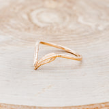 Shown here is "Fala", a 14K gold v-shaped band with feather accents, facing left.