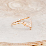 Shown here is "Fala", a 14K gold v-shaped band with feather accents, facing right.