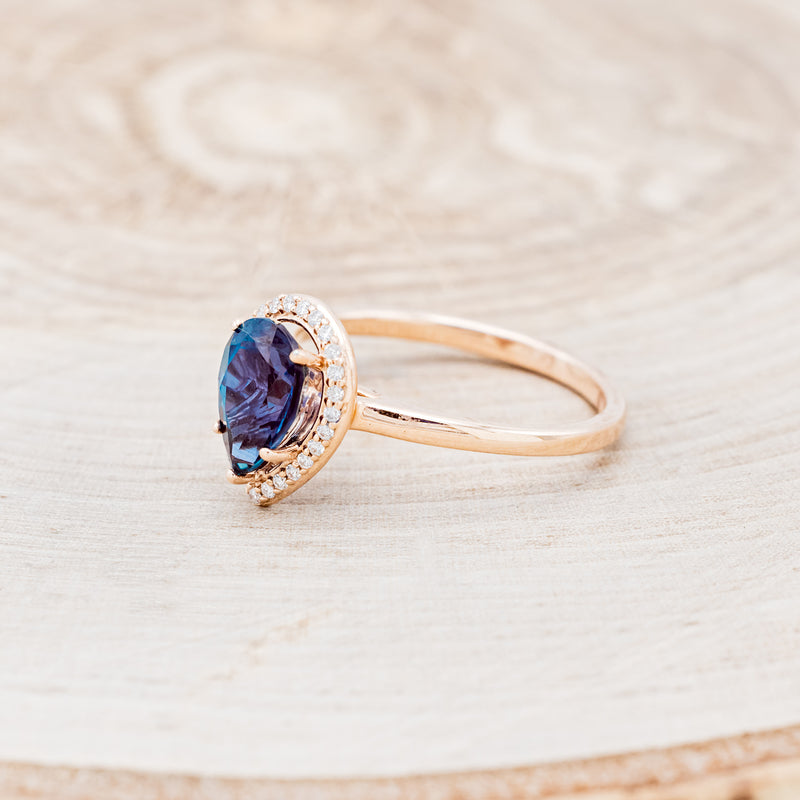 Shown here is "Clariss", a bridal suite-style lab-created alexandrite women's engagement ring with a diamond halo, facing left. Many other center stone options are available upon request.