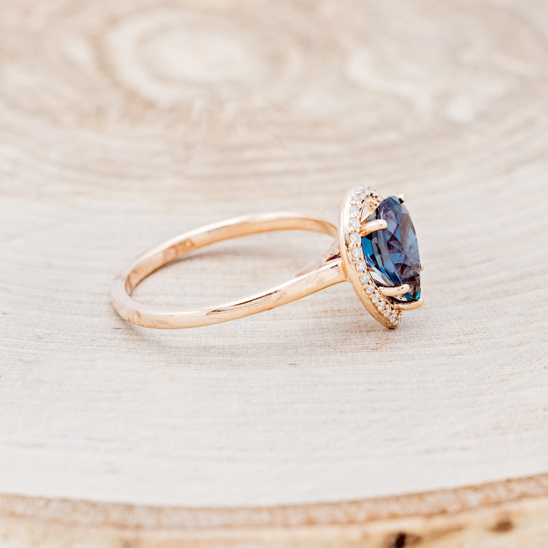 Shown here is "Clariss", a bridal suite-style lab-created alexandrite women's engagement ring with a diamond halo, facing right. Many other center stone options are available upon request.