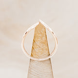 Shown here is "Fala", a 14K gold v-shaped band with feather accents, side view on stand.