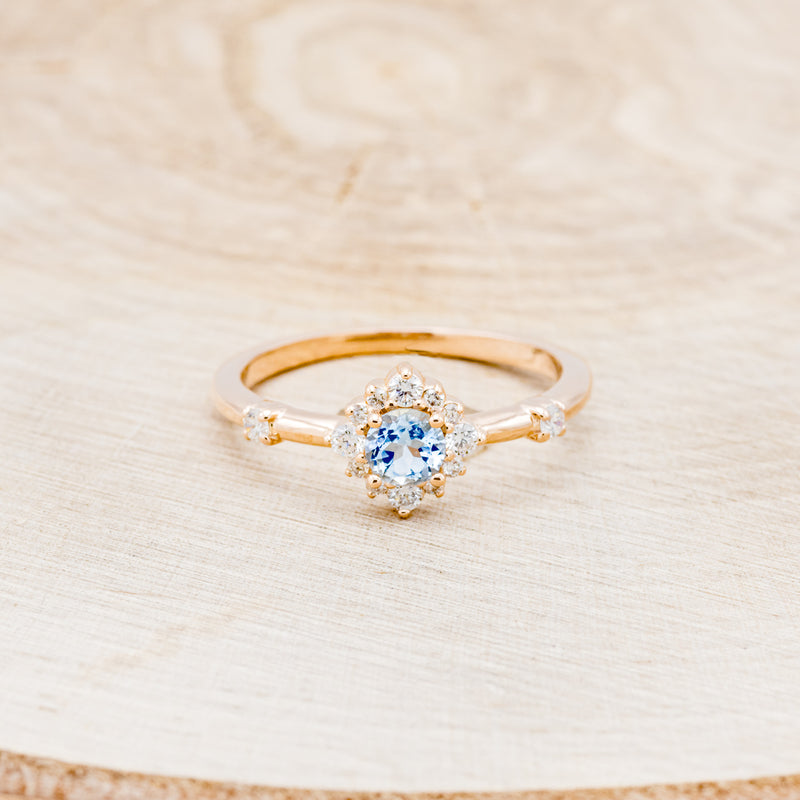 Shown here is "Starla", an aquamarine women's engagement ring with a starburst diamond halo, front facing. Many other center stone options are available upon request.